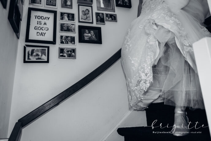 bruid komt van trap aflopen langs fotolijstjes met teksten en foto's