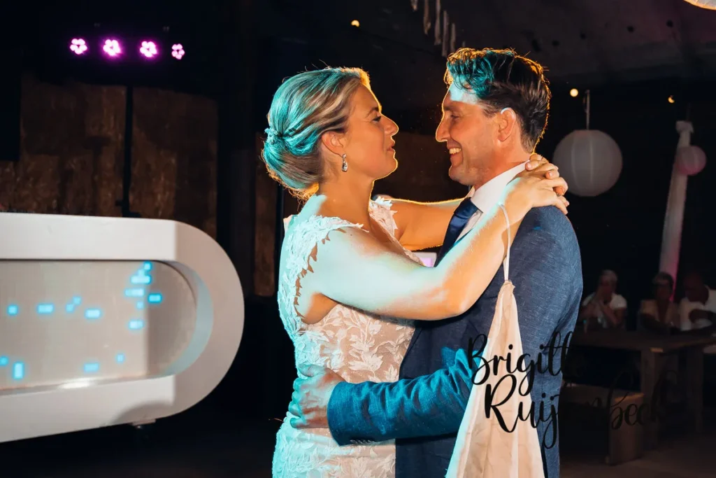 Fokke Jan en Wytske dansen hun openingsdans tijdens hun bruiloftsfeest, met een grote glimlach en liefdevolle blik op elkaar gericht.