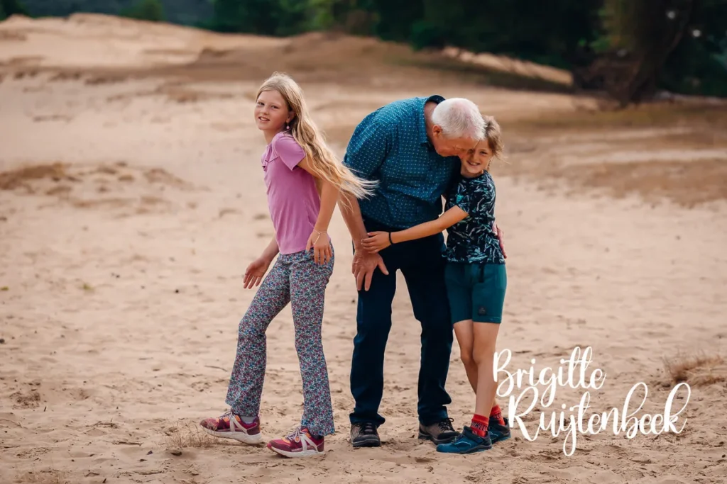 Opa wandelt lachend met twee kleinkinderen tijdens familiedag in de natuur