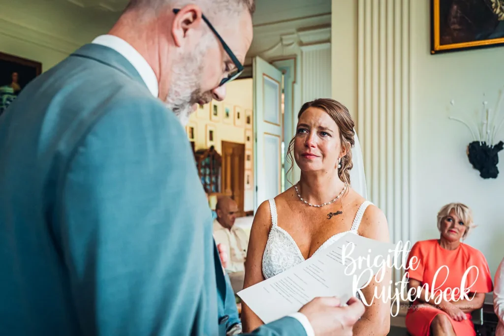 Bruid luistert geëmotioneerd naar de geloften van de bruidegom tijdens de ceremonie in de Fraeylemaborg.