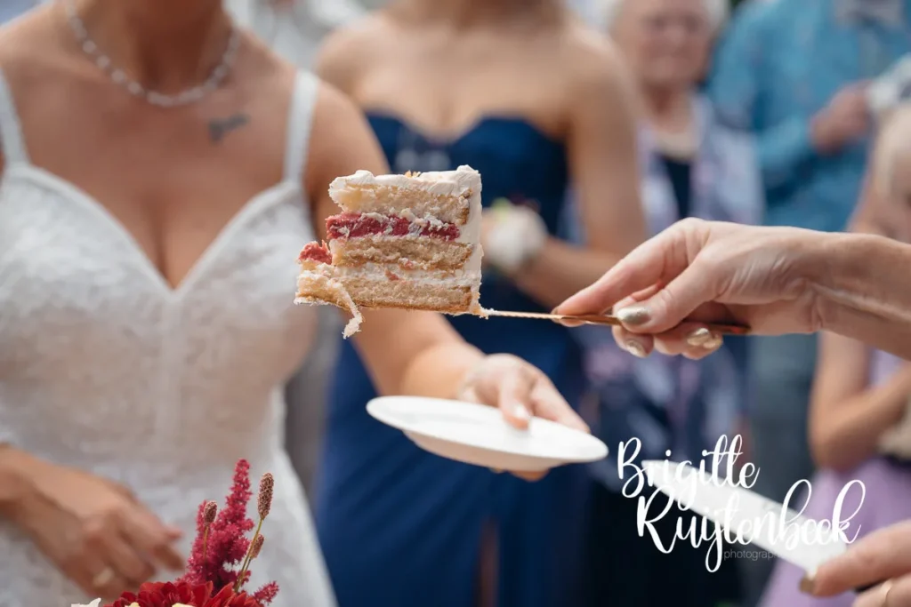Close-up van het serveren van een stuk bruidstaart met aardbeienvulling tijdens het huwelijksfeest.