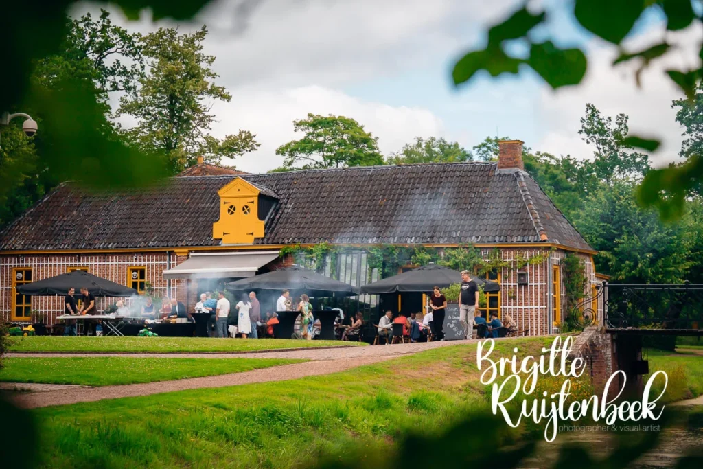 Gasten genieten van een gezellige barbecue in de tuin van Restaurant de Boerderij naast de Fraeylemaborg tijdens een zomerse bruiloft.