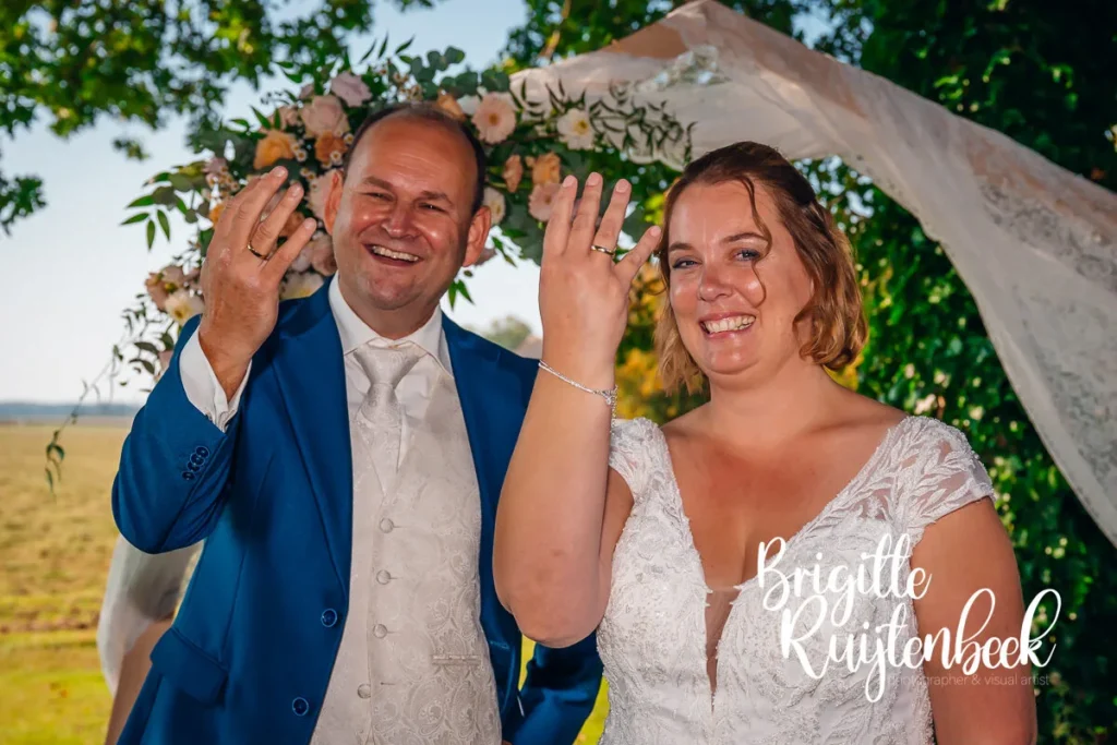 Bruidspaar Sandra en David toont trots hun trouwringen bij Boerderij Mausel in Noordbroek