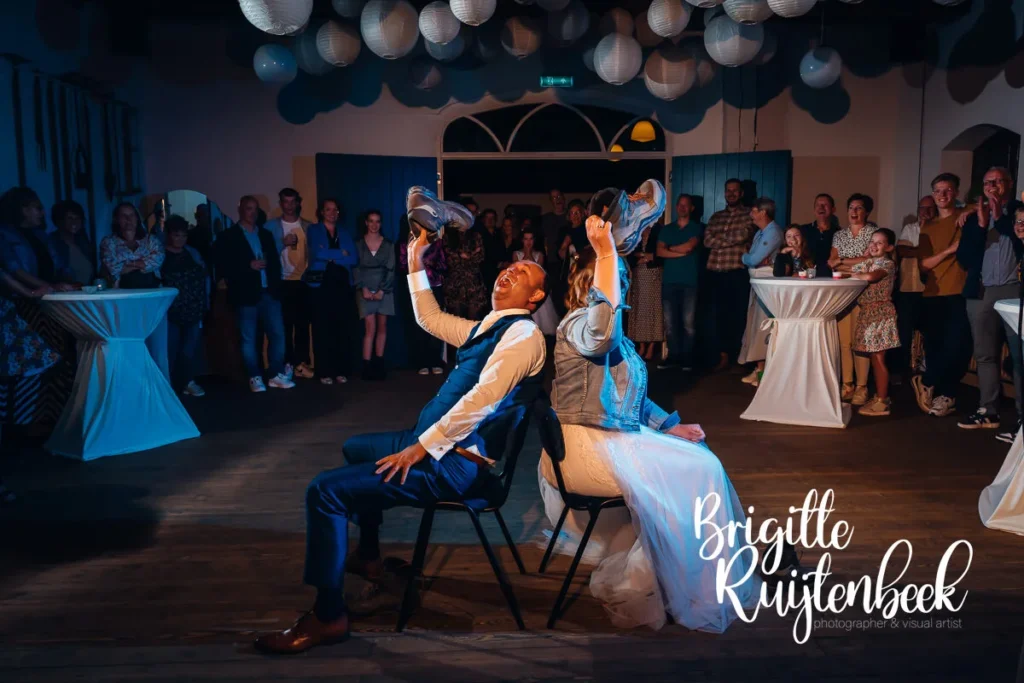 Bruidspaar speelt het schoenen­spel tijdens hun bruiloftsfeest bij Trouwboerderij Mausel.