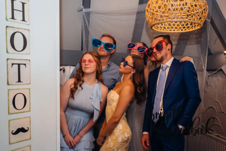 Trouwfeest De Wiemel Gasselte, gasten poseren met zonnebrillen in het fotohokje.