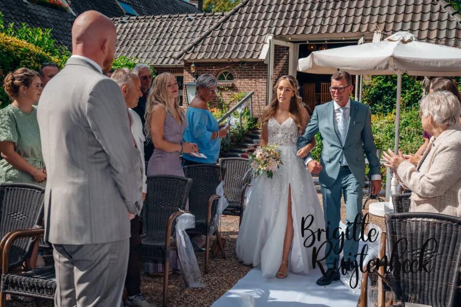 Bruidsfotografie De Wiemel Gasselte, bruid loopt met haar vader de ceremonie in.