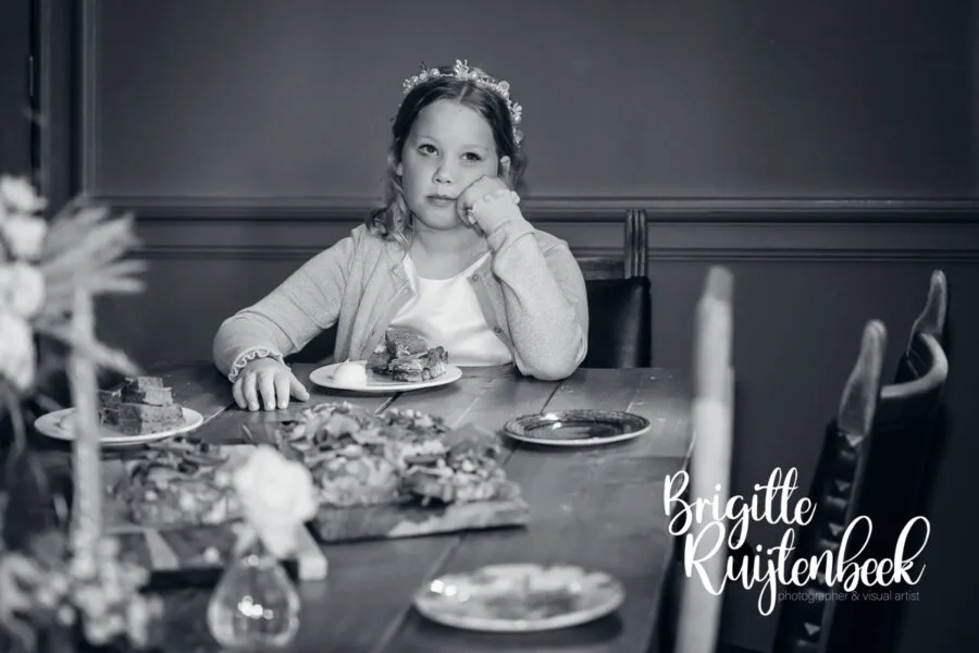 Kind zit met het hoofd op de hand aan tafel tijdens het diner op de bruiloft