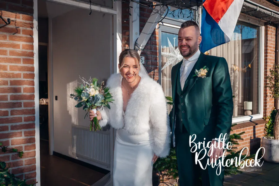 First look van bruid en bruidegom bij hun huis tijdens de voorbereidingen van hun winterbruiloft op kerstavond in Drenthe