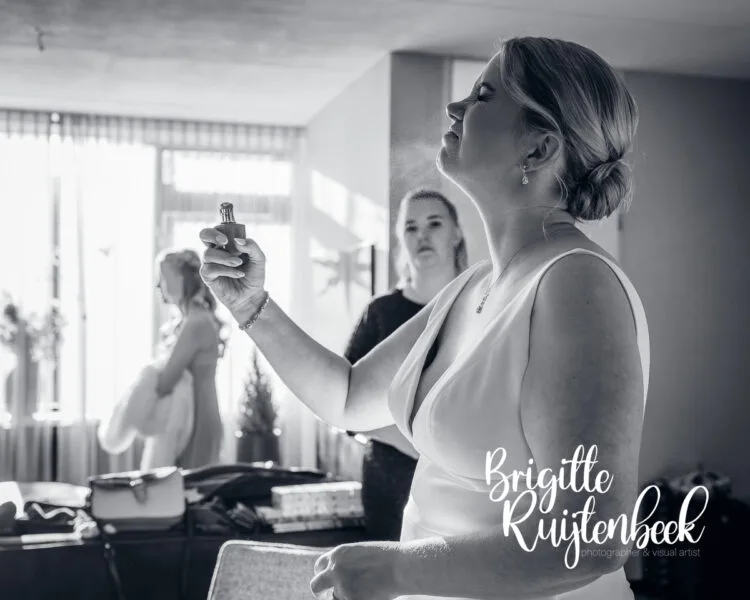 Bruid gebruikt parfum tijdens de voorbereidingen van haar winterbruiloft op kerstavond in Drenthe