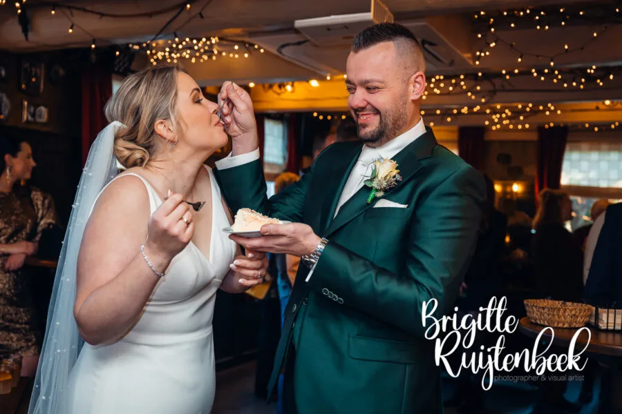 Bruidspaar voert elkaar taart tijdens de receptie van hun winterbruiloft bij De Kruimel in Gasselte