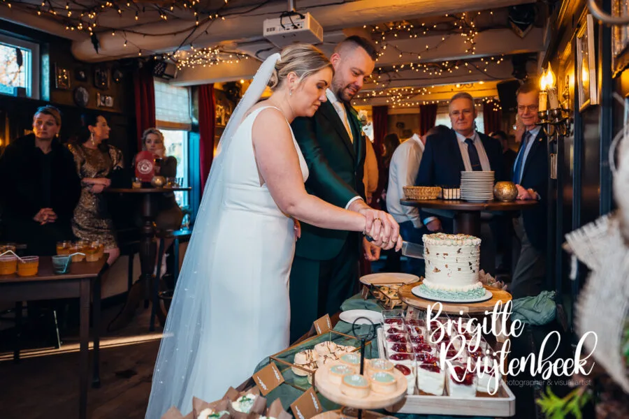 Bruidspaar snijdt samen de bruidstaart aan tijdens de receptie bij De Kruimel in Gasselte