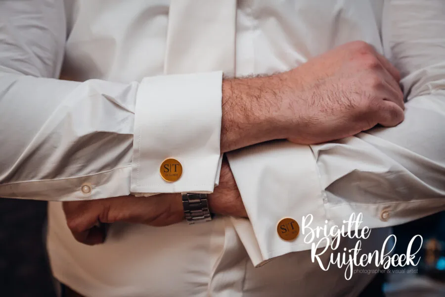 Detail van manchetknopen tijdens het aankleden van de bruidegom bij een winterbruiloft op kerstavond in Drenthe