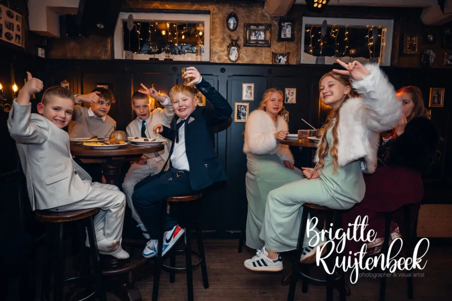 Kinderen zitten ontspannen aan de bar tijdens de avond van een winterbruiloft in Gasselte