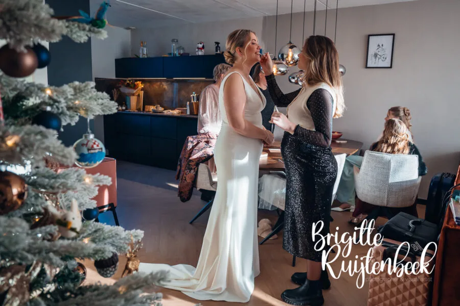 Bruid wordt opgemaakt in huis tijdens de voorbereidingen van een winterbruiloft op kerstavond in Drenthe