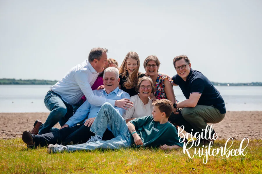 Drie generaties van één familie tijdens een ontspannen familieshoot op het strand van het Oldambtmeer in Groningen.
